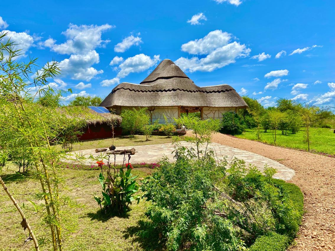 Bamboo Village Safari Lodge's gedekte hoofdgebouw ingebed in zijn tuin, Murchison Falls