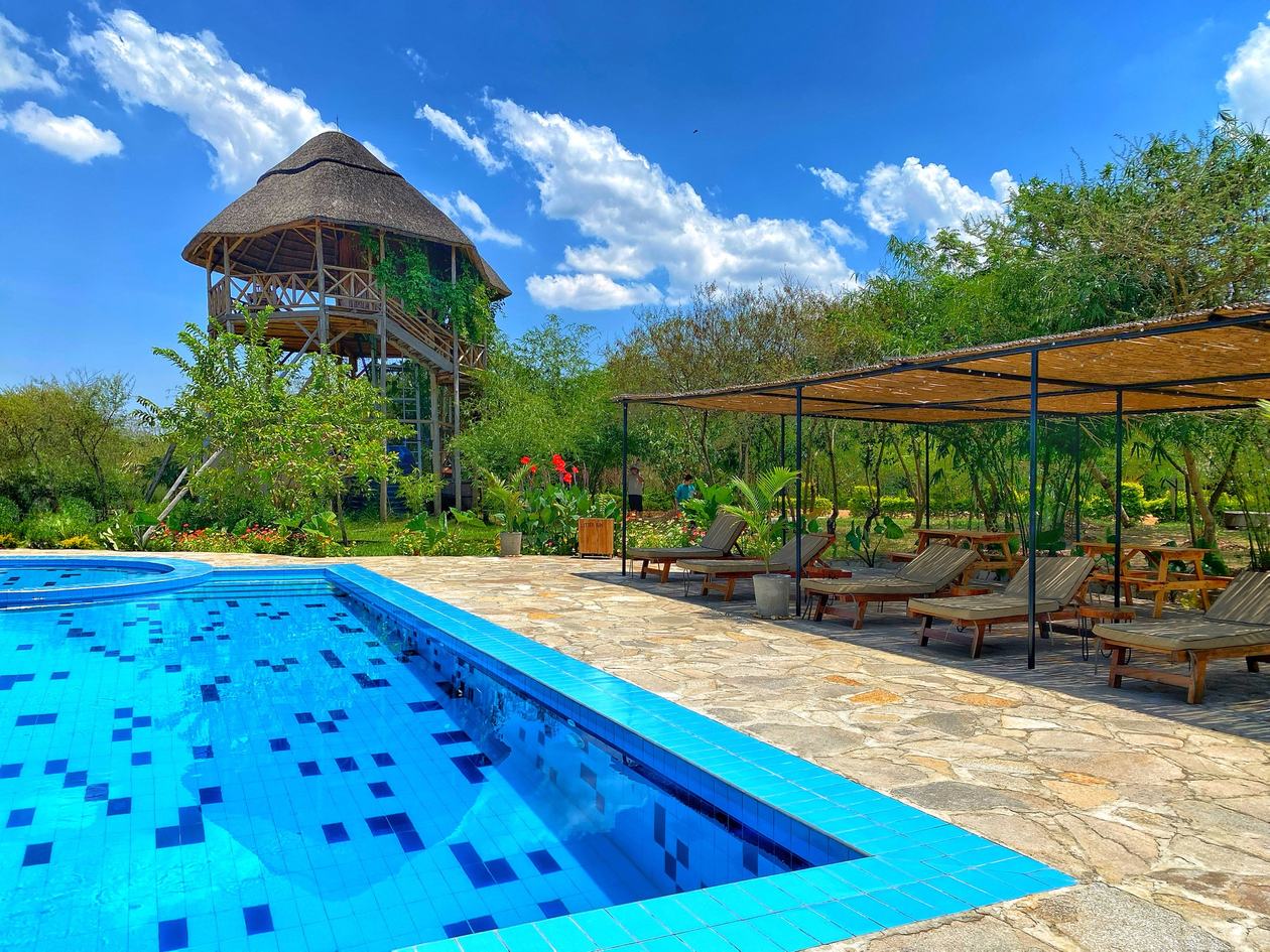 Swimmingpool und Liegestühle unter dem Aussichtsturm bei der Bamboo Village Safari Lodge