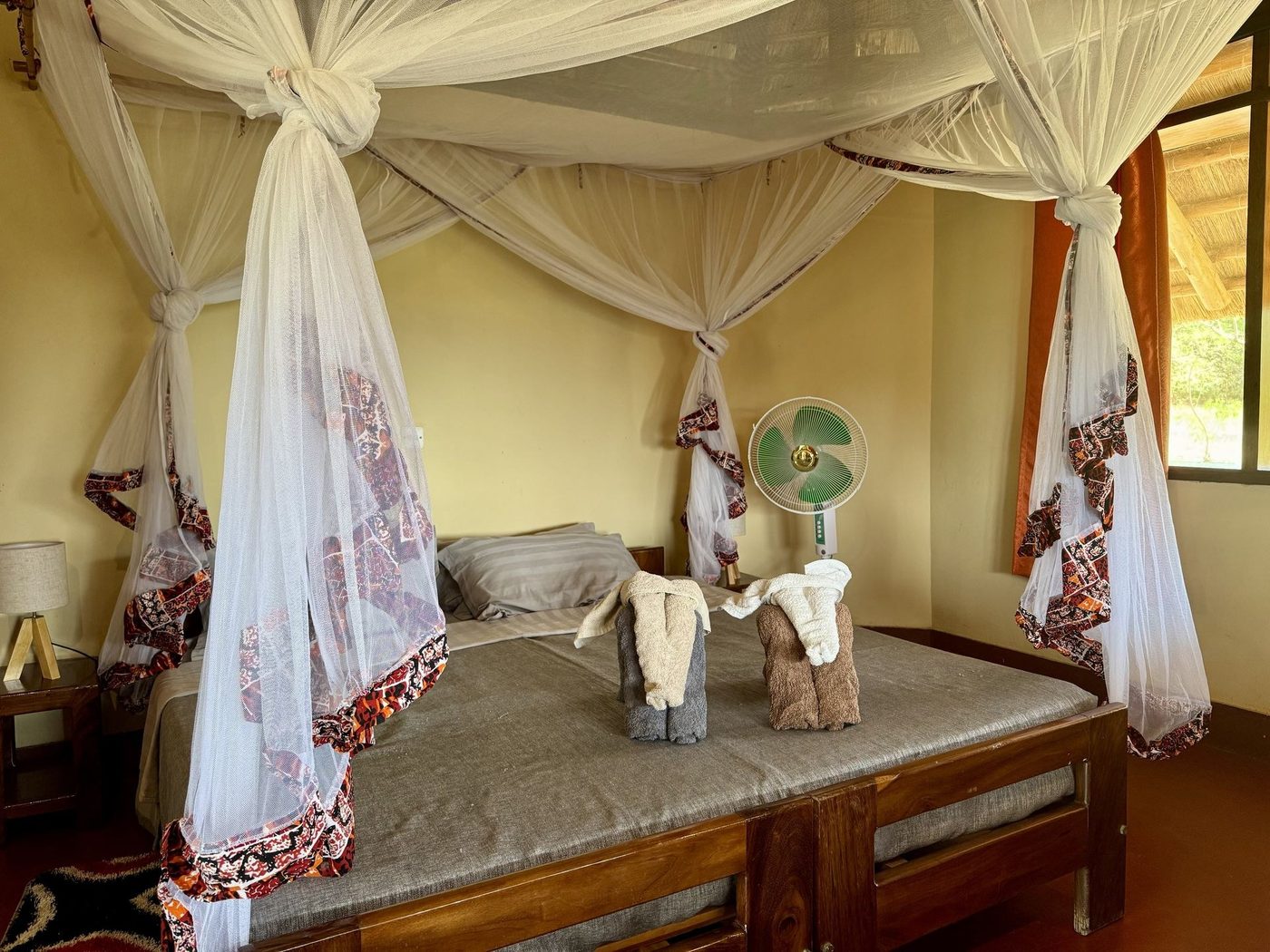 Lits jumeaux sous un dais à l'intérieur d'un cottage au toit de chaume au Bwana Tembo Safari Camp