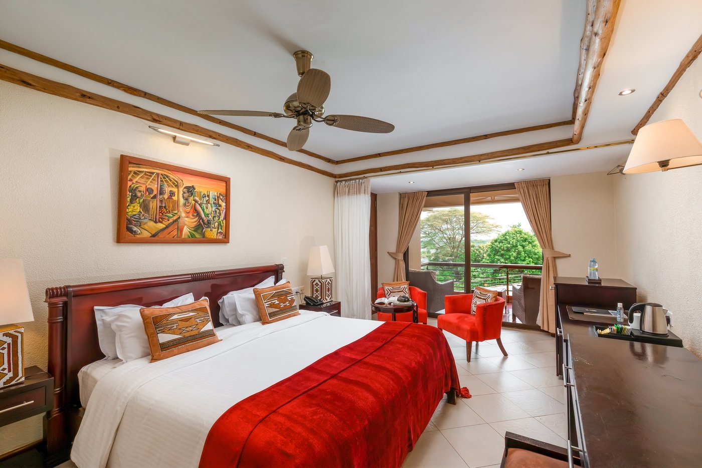 Chambre avec literie rouge et fauteuil près de la fenêtre à Chobe Safari Lodge