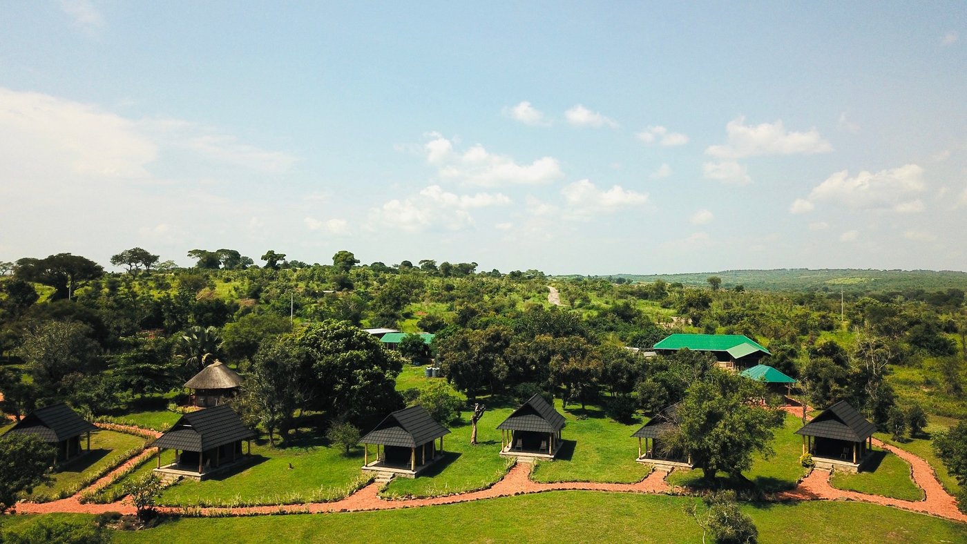Luchtfoto van Fort Murchison's gedekte hutten tussen tuinen en bush in Murchison Falls