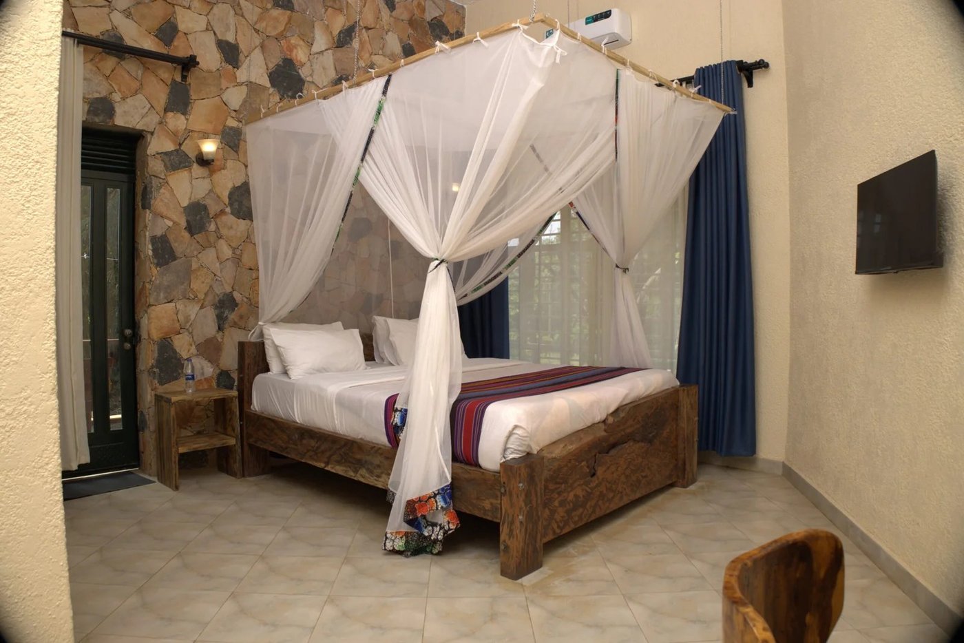Bett mit Moskitonetz an einer Stein-Akzentwand im Kabalega Resort Masindi
