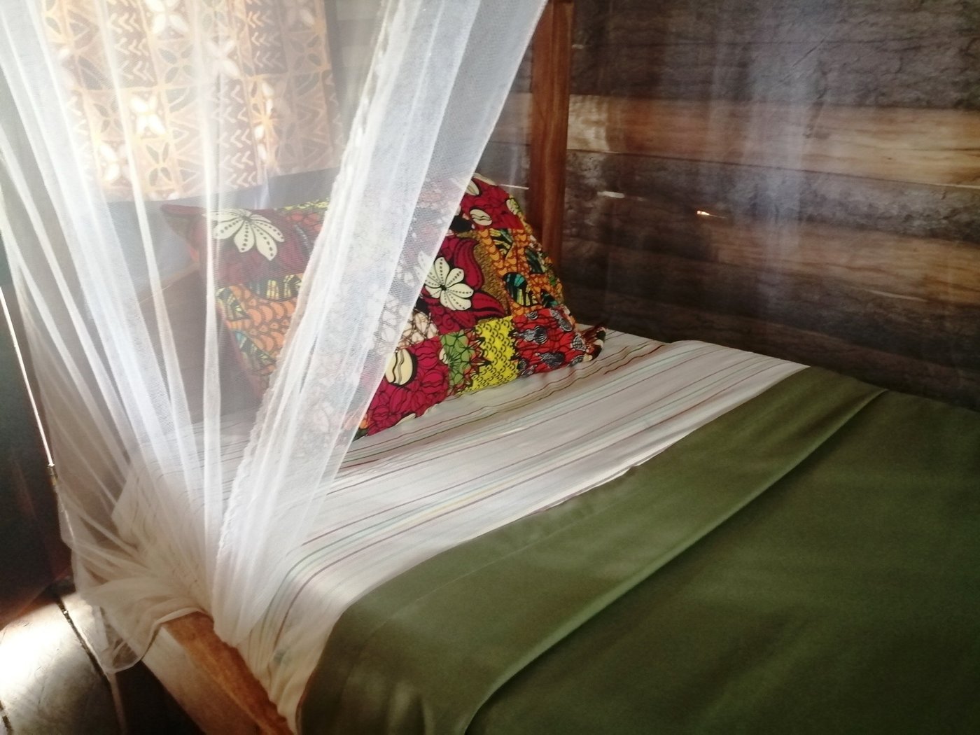Lit à moustiquaire avec un coussin à motifs dans une chambre privée de Murchison Backpackers