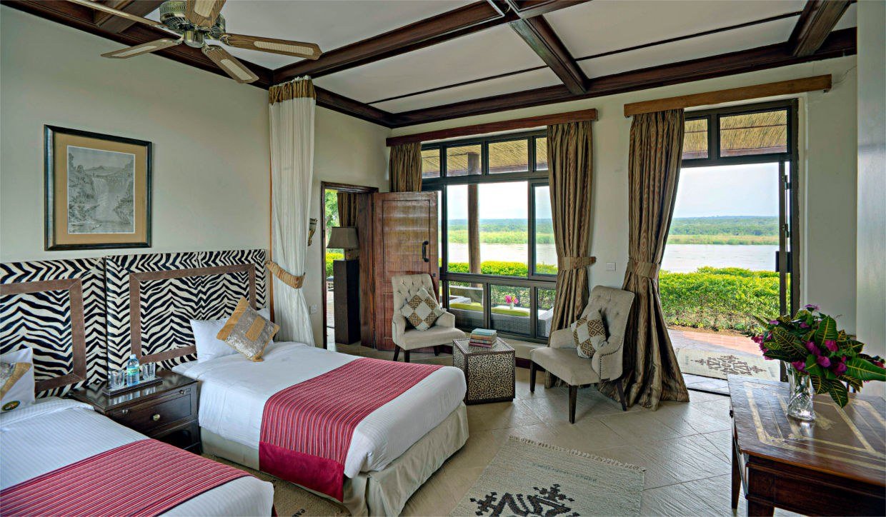 Zwillingsbetten mit Zebrastreifenbezügen neben dem Balkon in der Paraa Safari Lodge