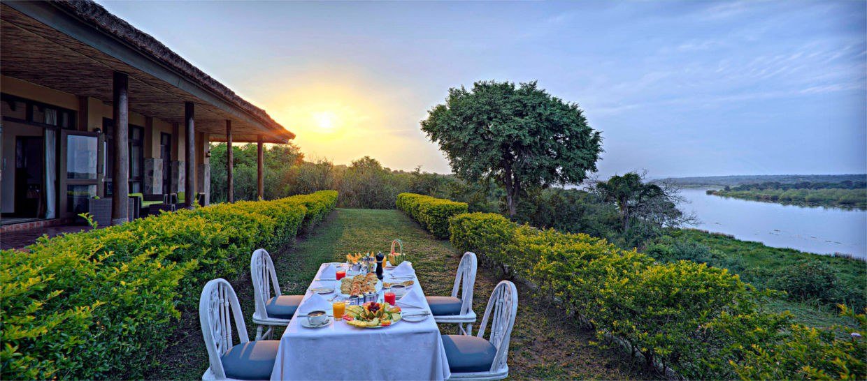 Frühstückstisch auf dem Rasen mit Blick auf den Fluss in der Paraa Safari Lodge