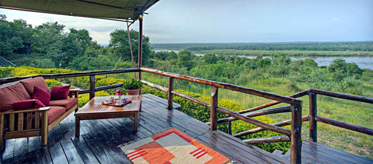 Rotes Sofa auf der Veranda mit Blick auf die Savanne in der Paraa Safari Lodge