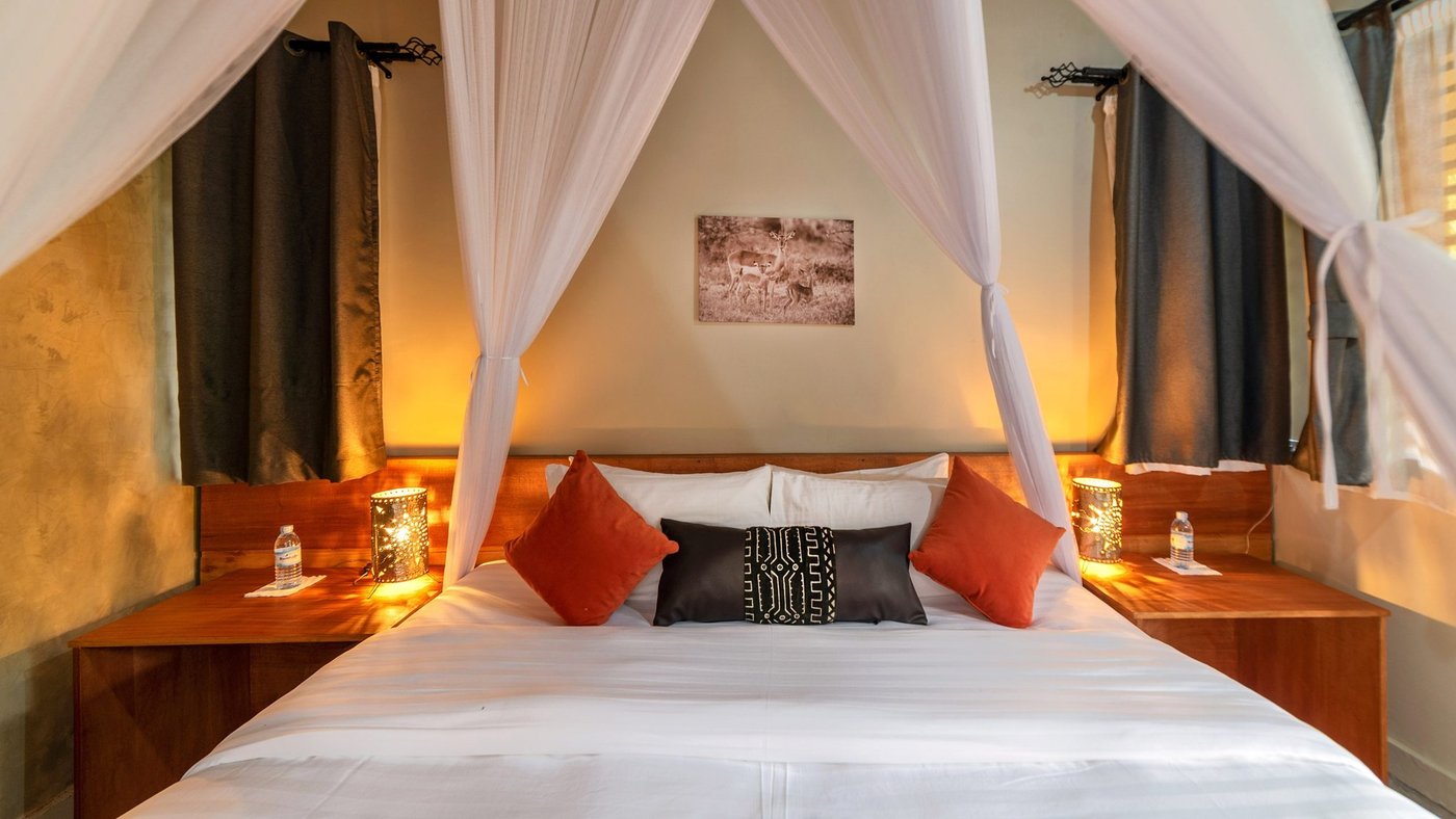 Lit avec moustiquaire et oreillers d'accent orange au Sambiya River Lodge