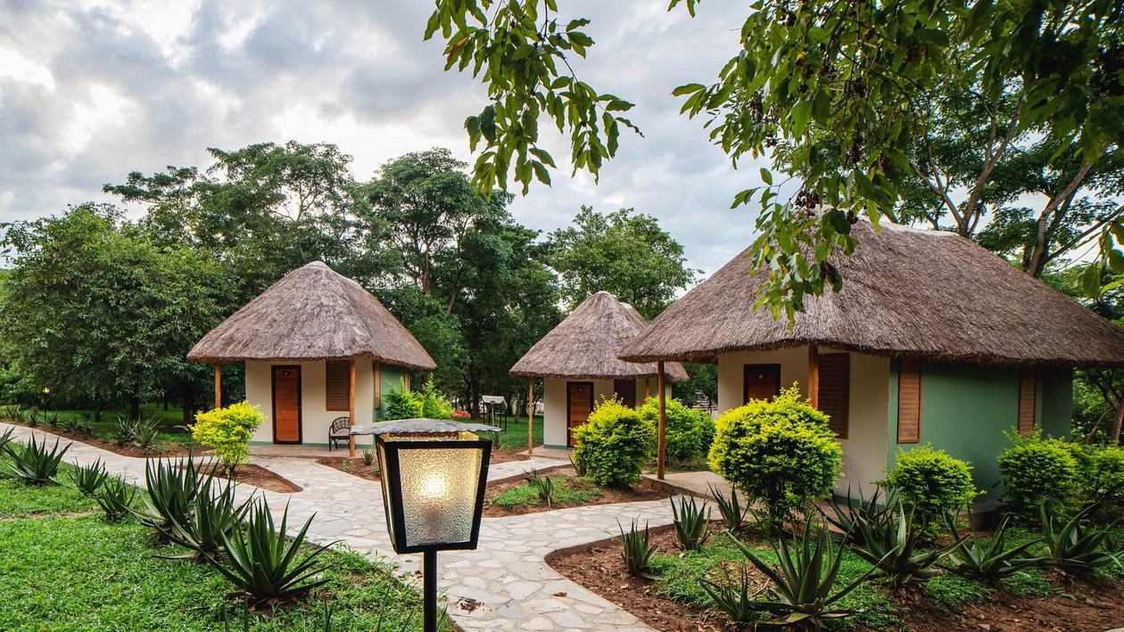 Allée bordée de cottages ronds aux toits de chaume et d'éclairages de jardin au Sambiya River Lodge